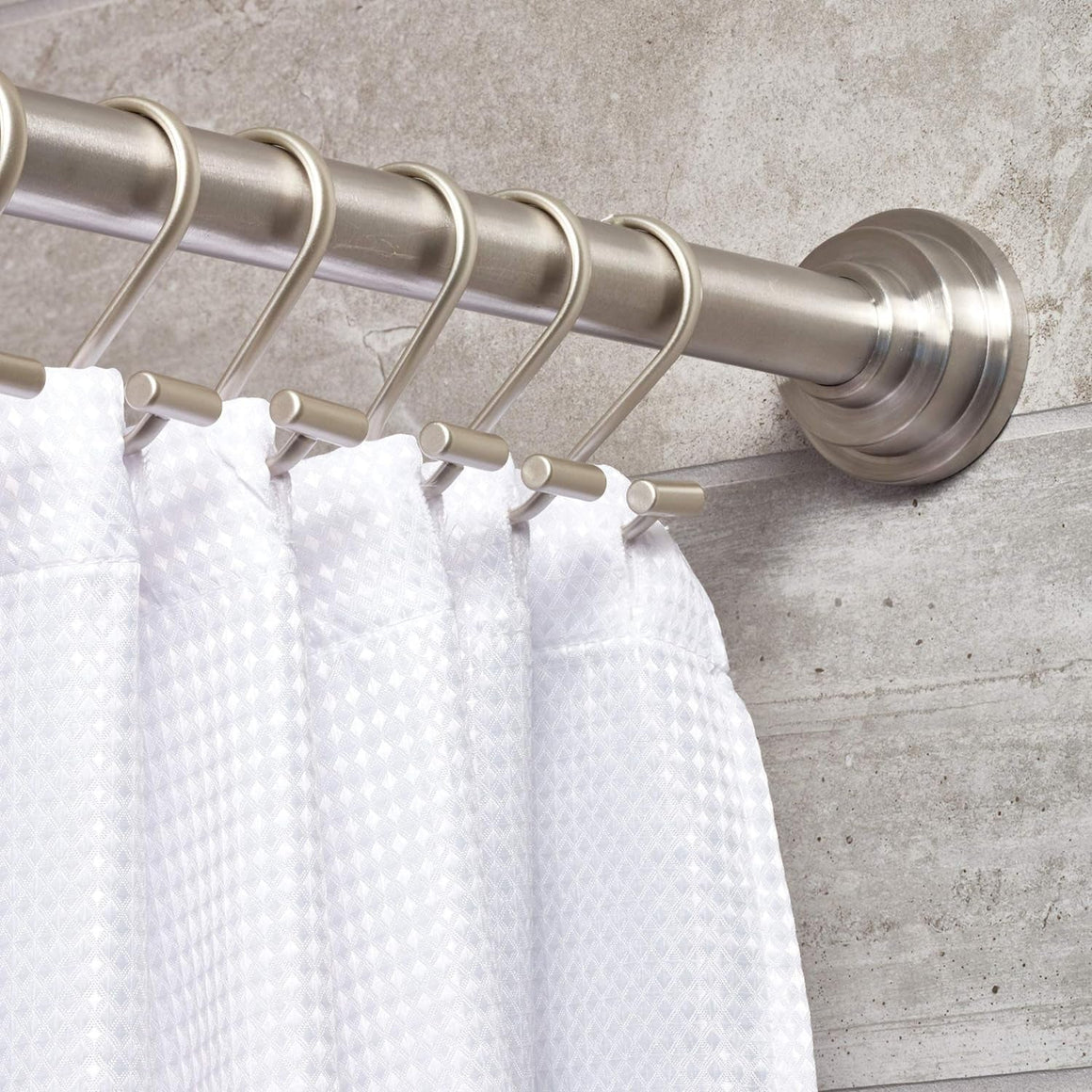 Metal shower curtain rings installed on a standard rod holding a white curtain in a bathroom setting